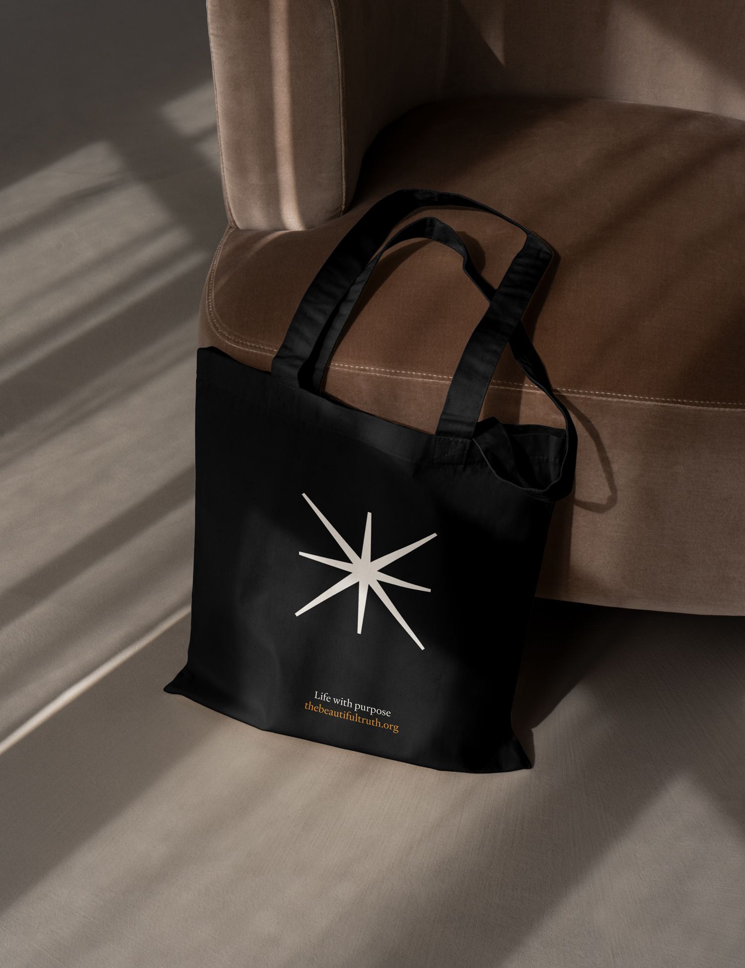 A black tote bag with the north star logo created as part of the brand identity for The Beautiful Truth